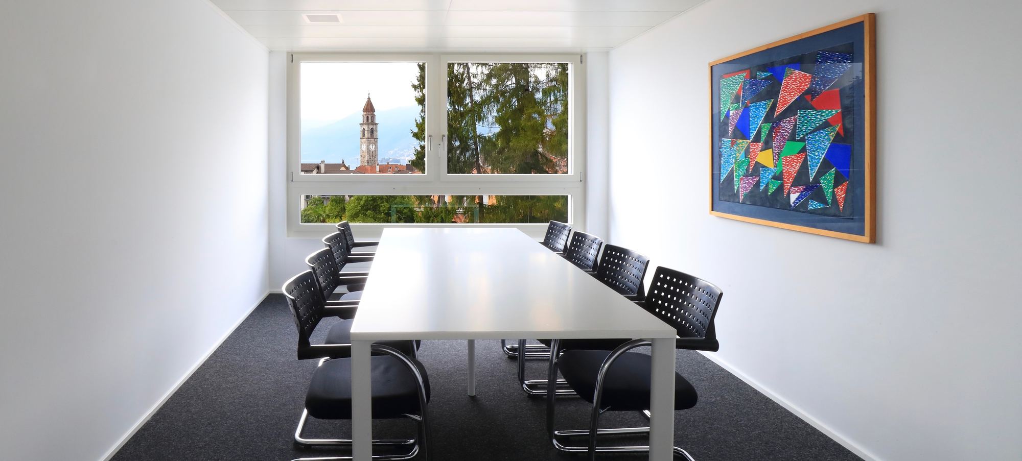 La sala riunioni dello studio, con la finestra sui tetti e un quadro astratto alla parete